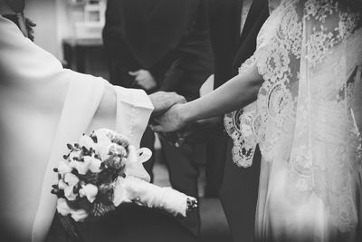 Midsection of bride and groom doing wedding ceremony in church