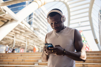 Man wearing headphones using smart phone outdoors