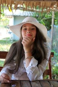 Portrait of beautiful woman with hand on chin wearing hat