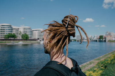 Close-up of man with dreadlocks standing by river in city