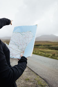 Midsection of man holding umbrella on road against sky