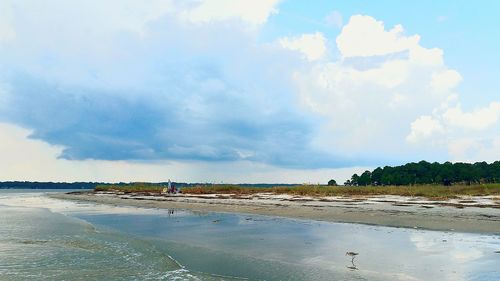Scenic view of beach against cloudy sky