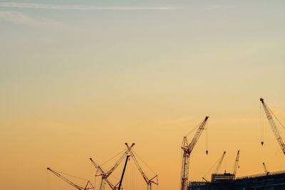 Cranes against sky during sunset