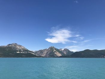 Scenic view of sea and mountains against blue sky