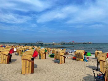 Hooded chairs on beach against sky