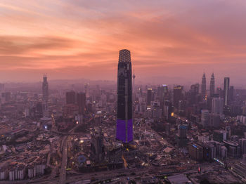 Modern buildings in city against sky during sunset