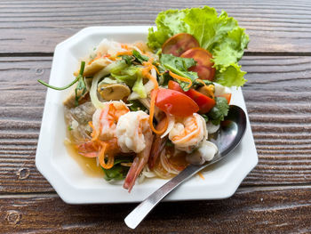 Closeup of the spicy thai seafood salad served in the white plate in the thai restaurant.