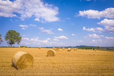 Hay bales on field against sky