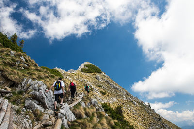 Low angle view of people on mountain against sky