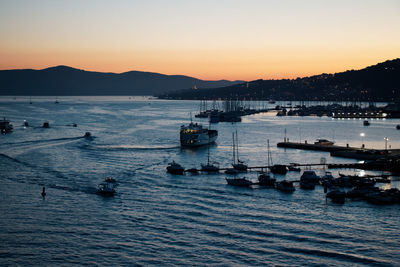 Sailboats in sea at sunset