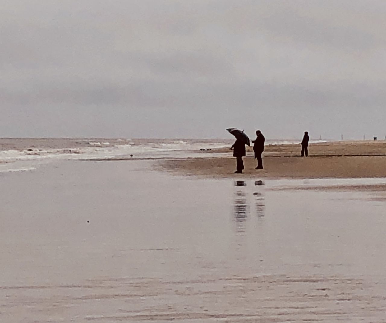MEN WALKING ON BEACH AGAINST SKY DURING SUNSET