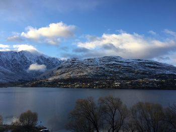 Scenic view of lake by snowcapped mountains against sky