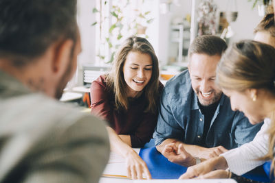 Cheerful male and female entrepreneurs at table during meeting in creative office