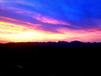 Scenic view of silhouette mountains against dramatic sky