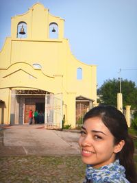 Portrait of smiling woman against clear sky in city