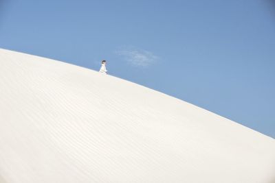 Low angle view of woman standing on sand dune against sky