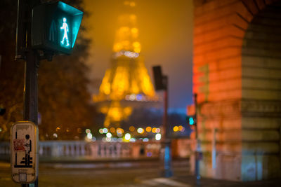 Illuminated street light by building at night