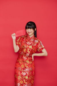 Portrait of beautiful young woman against red background