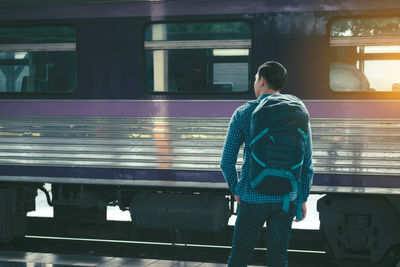 Rear view of man standing against train at railroad station