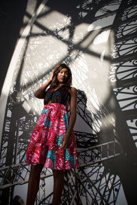 Portrait of beautiful young woman standing against wall