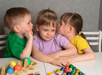 Children paint eggs. children whisper and secret. getting ready for easter.