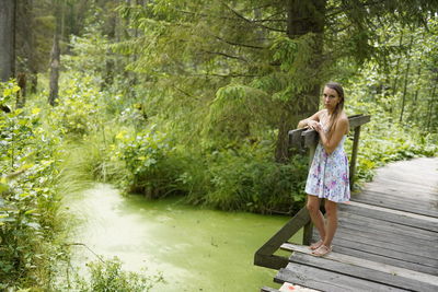 Woman standing by plants in forest