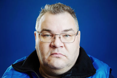 Close-up portrait of young man against blue background