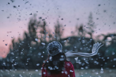 Rear view of woman standing on field during snowfall