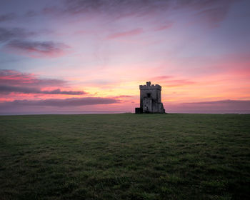 Built structure on field against sky during sunset