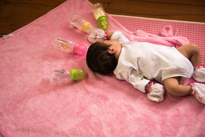 High angle view of baby sleeping on bed by milk bottles at home