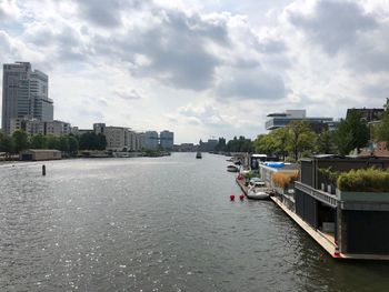 Buildings by river against sky in city