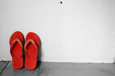 Pair of red slippers leaning against wall