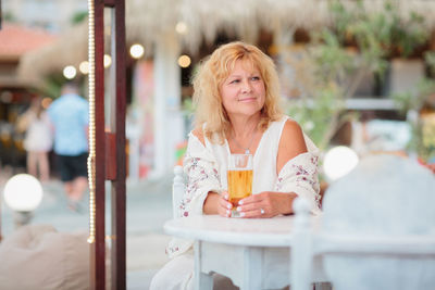 Portrait of woman drinking beer at beach cafe