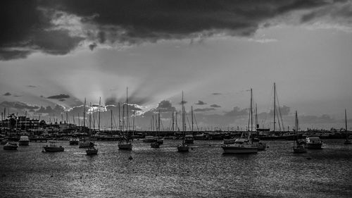 Boats moored at harbor against sky