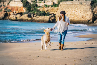 Full length of woman with dog on beach