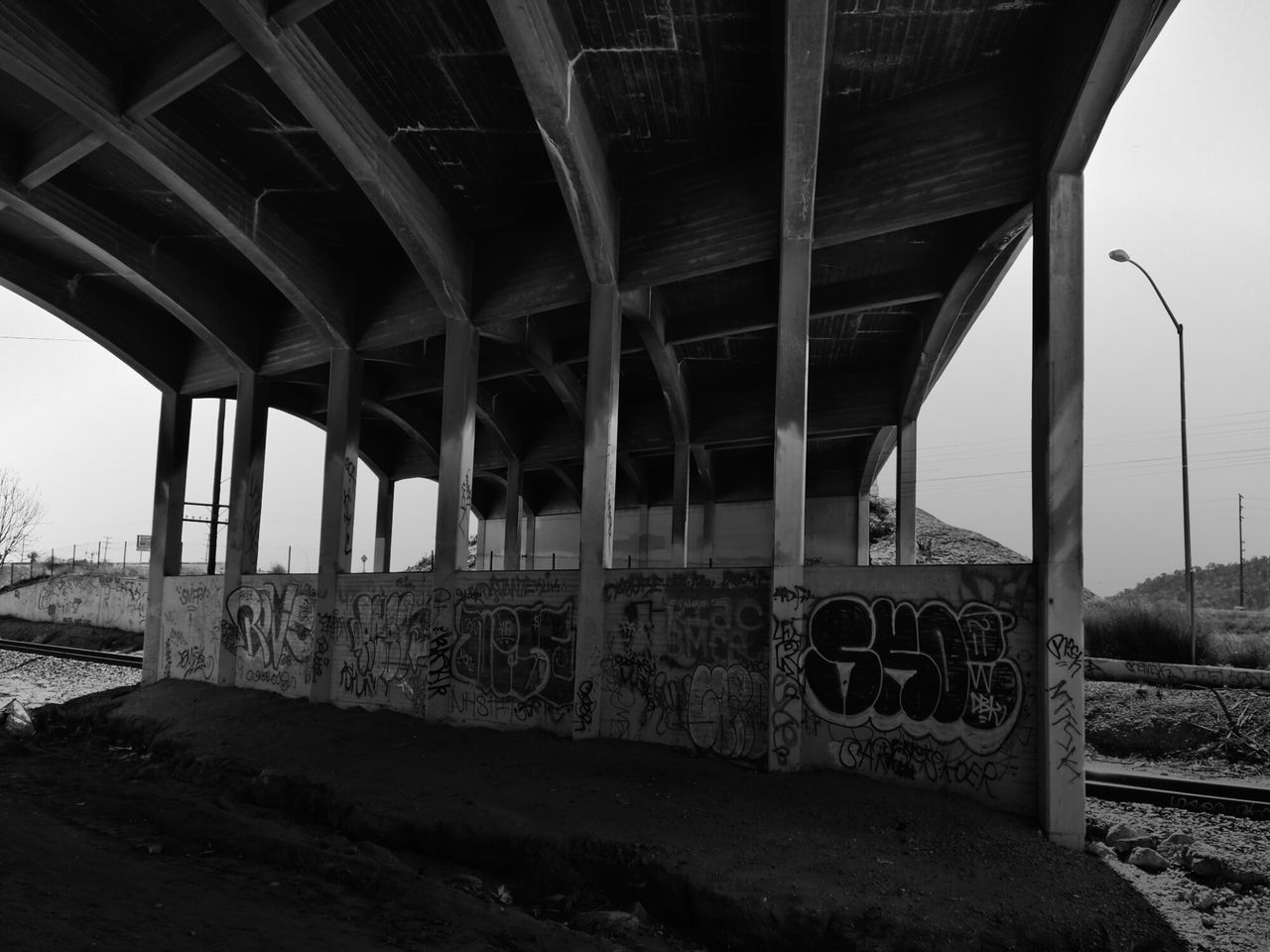 built structure, architecture, bridge - man made structure, connection, transportation, engineering, architectural column, abandoned, bridge, day, metal, low angle view, graffiti, obsolete, sunlight, old, sky, no people, indoors, clear sky