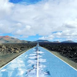 Road leading towards mountain against sky