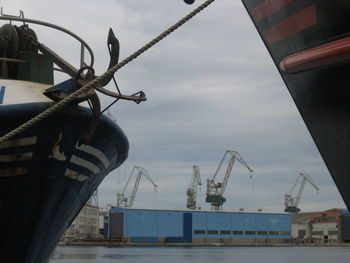 Cranes at harbor against sky