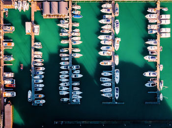 Aerial view of boats moored by piers at harbor in city