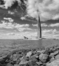 View of rocks on beach against cloudy sky