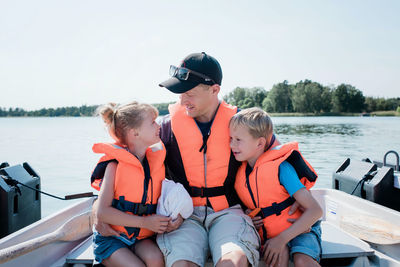 Father sat hugging his kids on a rowing boat in summer in sweden