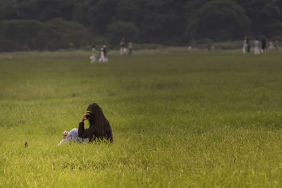 Woman sitting on grassy field