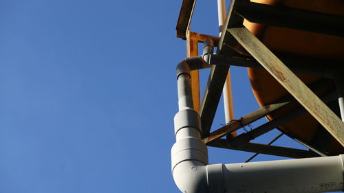 Low angle view of crane against clear blue sky