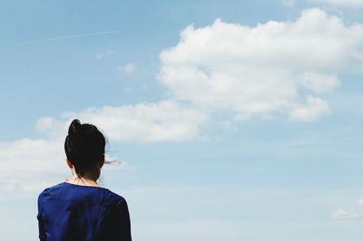 Rear view of woman standing against cloudy sky