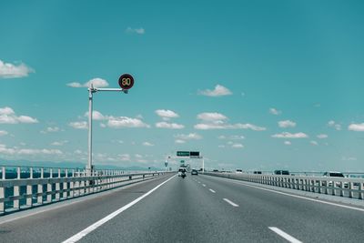 Diminishing perspective of highway against blue sky during sunny day