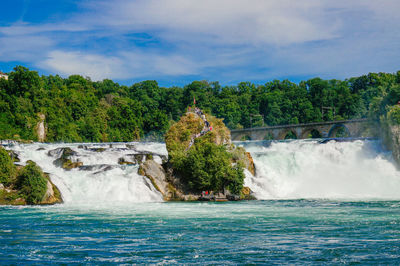 Scenic view of waterfall against cloudy sky