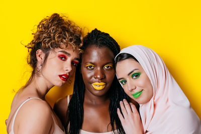 Portrait of beautiful young woman against yellow background