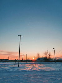 Scenic view of snow covered field against clear sky during sunset