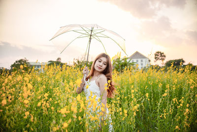 Portrait of beautiful woman standing on field against sky