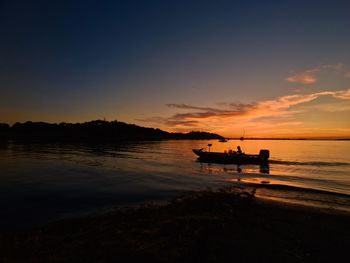 Boats in sea at sunset